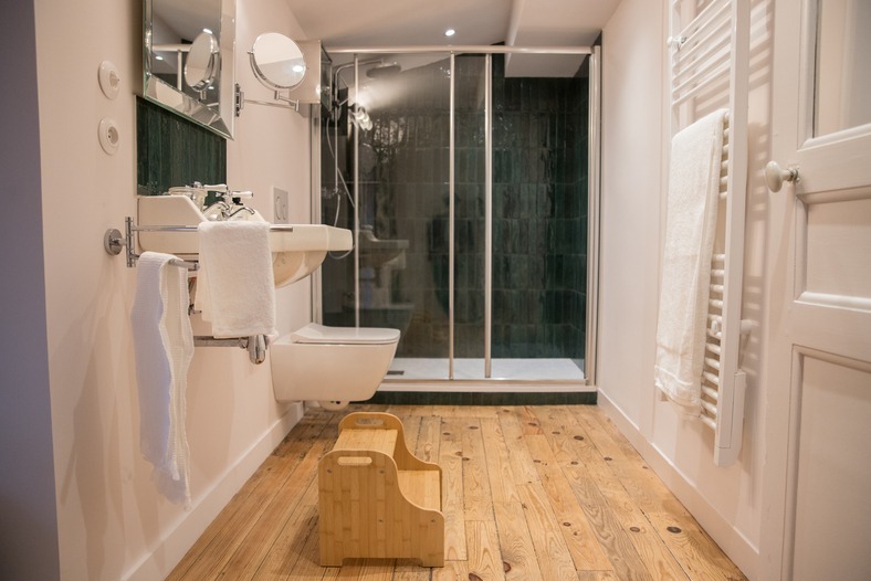 Salle de bain lumineuse composée d'une douche, de toilette et d'un lavabo.